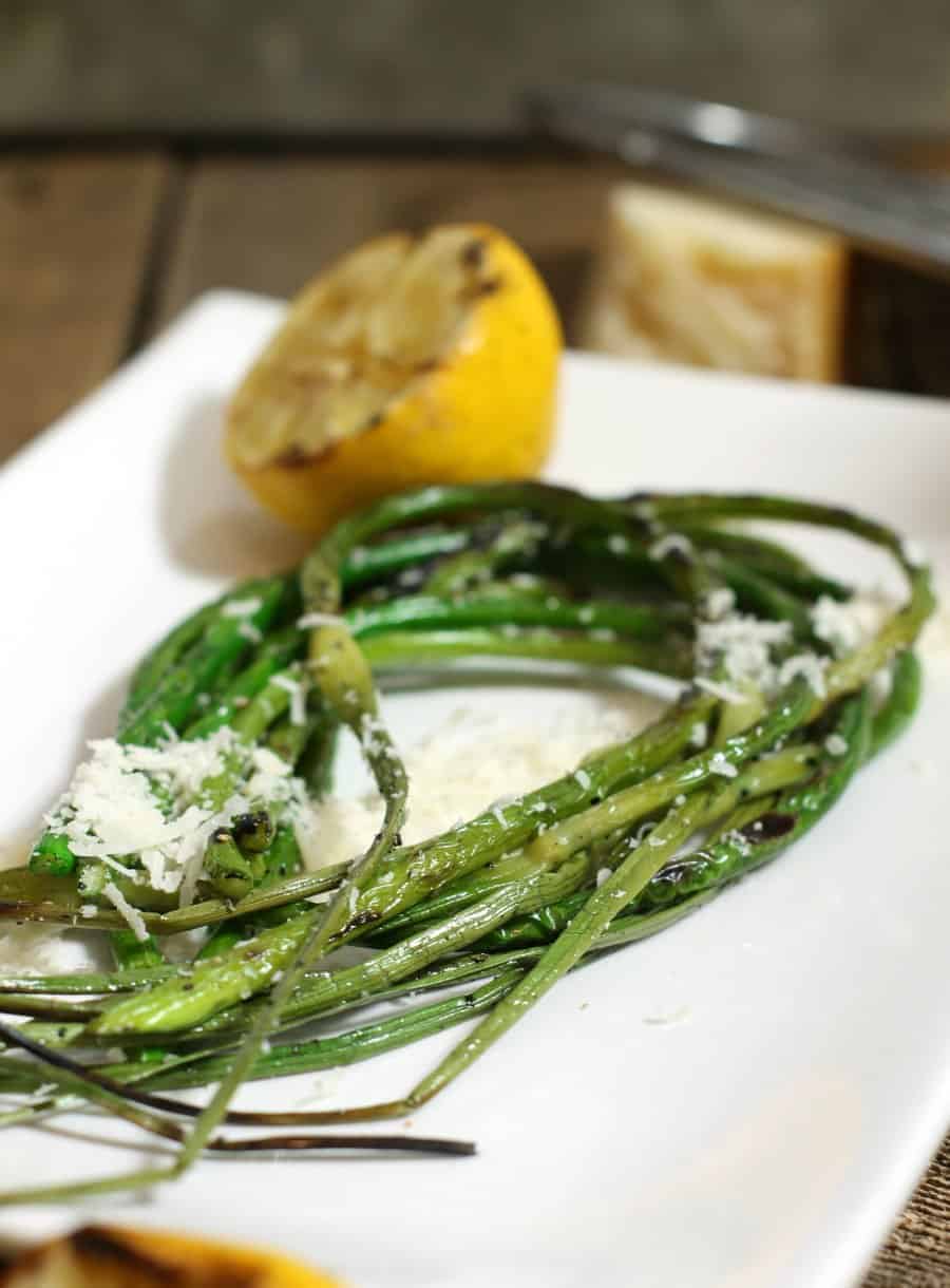 Grilled garlic scapes garnished with lemon and grated parmesan
