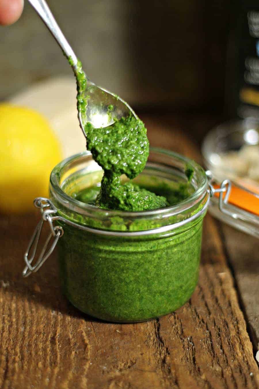 freshly made toasted almond and arugula pesto dripping from a spoon