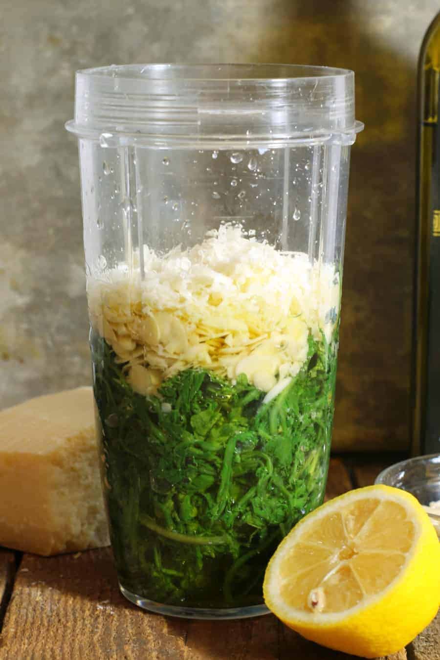 all ingredients needed to make arugula pesto in a blender