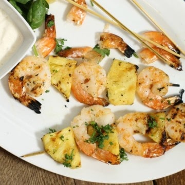 Grilled shrimp and pineapple skewers on a white platter