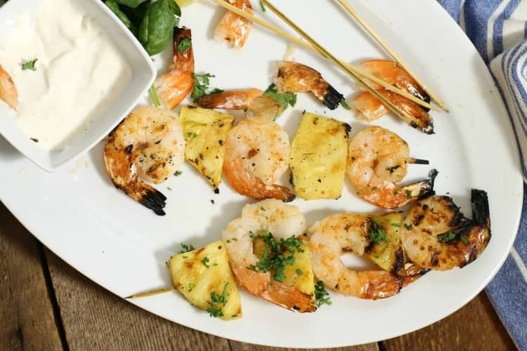 Grilled shrimp and pineapple skewers on a white platter