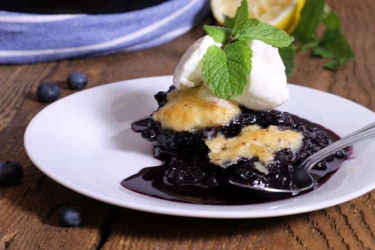 a plate of blueberry grunt topped with whipped cream and mint