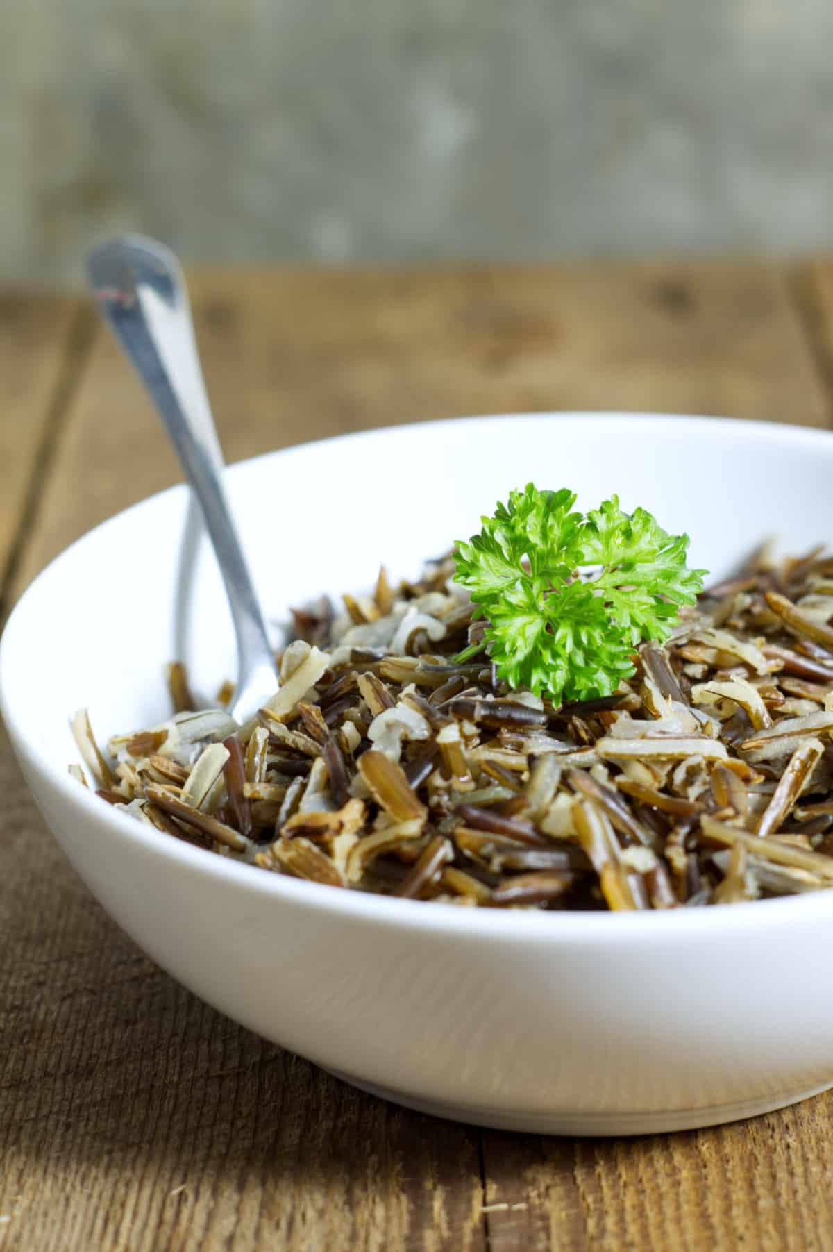 a white bowl filled with cooked wild rice and garnished with parsley