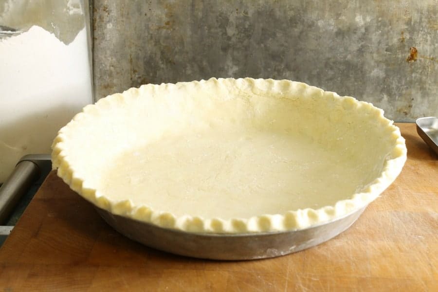 A raw uncooked pie crust in a pie pan ready for blind baking