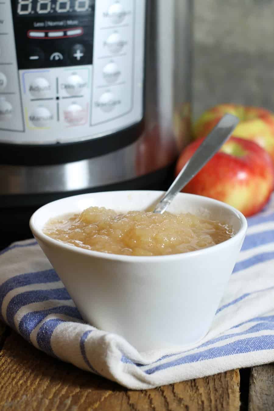 a vertical image of a white bowl of instant pot applesauce