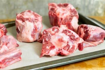 Raw oxtail bones on a sheet tray ready for roasting.