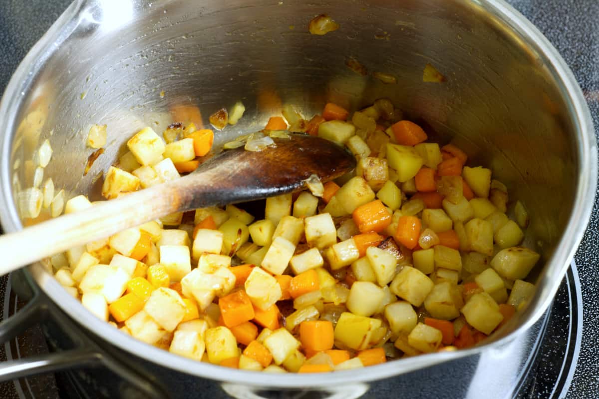 diced root vegetables sauteeing in a pot with butter