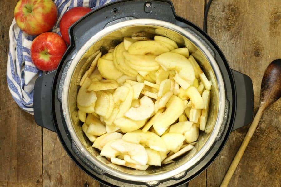 a top down viw of an open instant pot filled with sliced apples spices and water