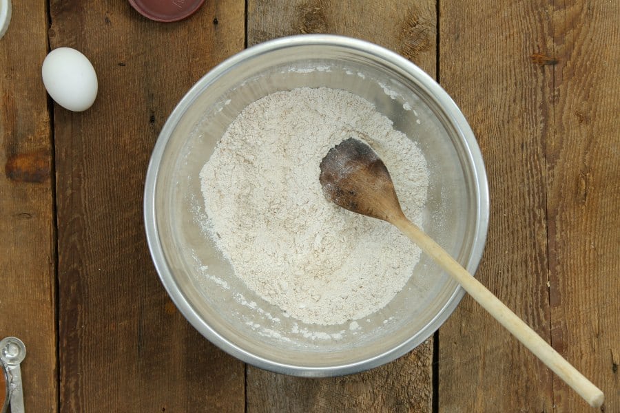 dry ingredients for blueberry bran muffins in a steel bowl on a wooden backdrop