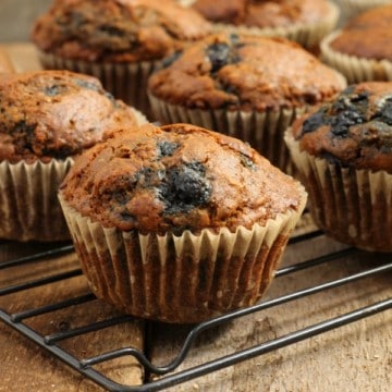 close up of blueberry bran muffins cooling on a black wire rack