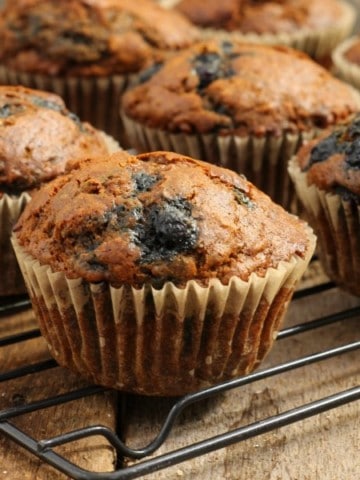 close up of blueberry bran muffins cooling on a black wire rack