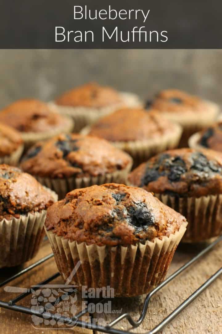 close up shot of a blueberry bran muffin on a cooling rack. overlaid with a banner reading blueberry bran muffins at the top