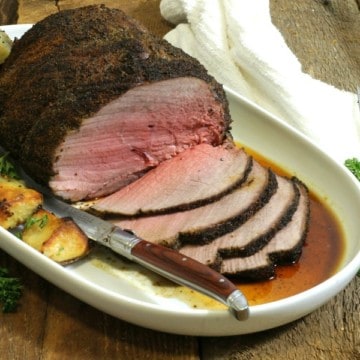 a sliced coffee rubbed sirloin tip roast on a white platter