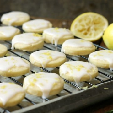 Glazed lemon shortbread cookies on a black cooling rack