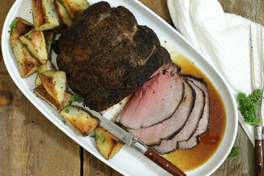 an overhead shot of a sliced coffee crusted sirloin tip roast on a white platter