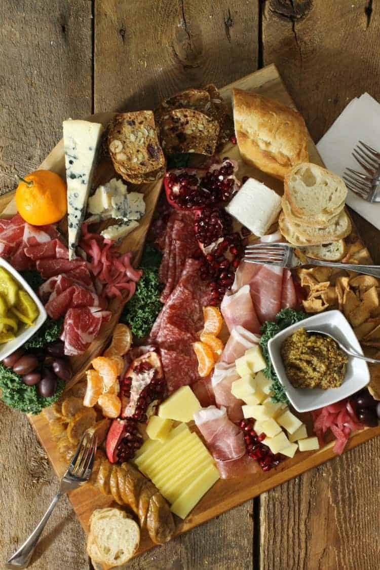 overhead view of a rustic looking meat and cheese tray - charcuterie board platter - on a wood board surface