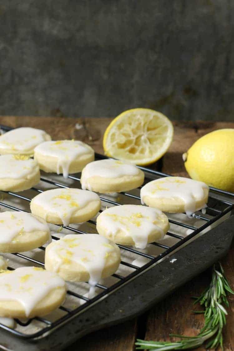 vertical image of glazed lemon shortbread cookies on a black cooling rack