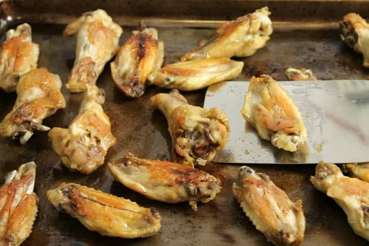 oven baked chicken wings being flipped.