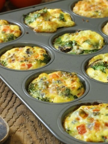 Three different kinds of breakfast egg muffins in a twelve cup muffin tin