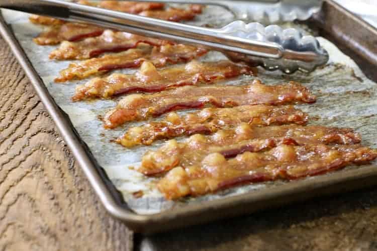 close up of perfectly cooked oven baked bacon strips on a parchment lined sheet pan