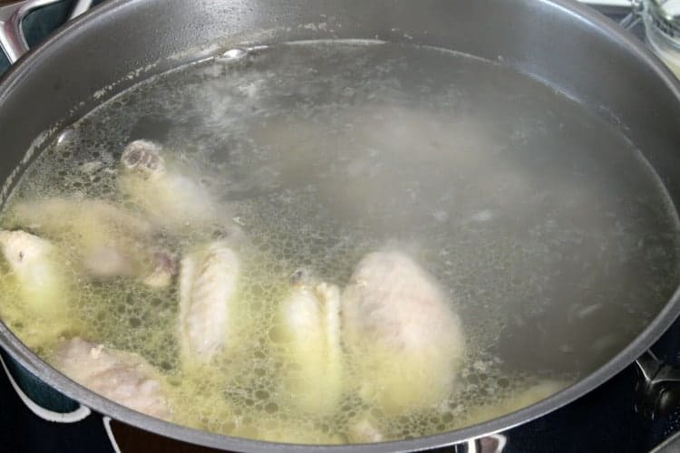chicken wings parboiling in a pot of water