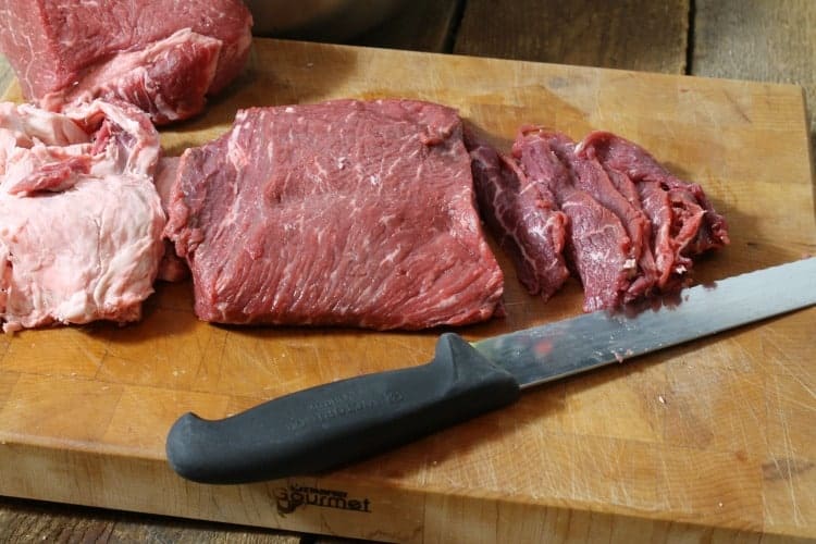 raw beef being sliced by hand for beef jerky