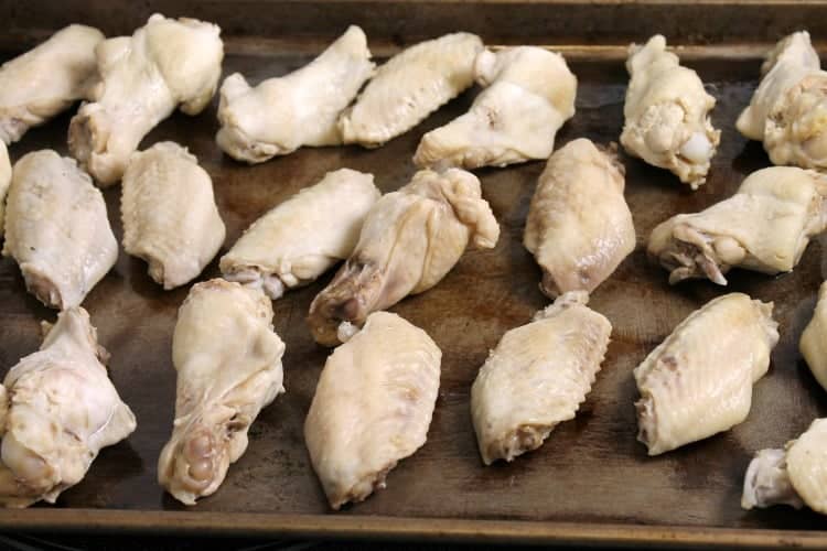 blanched chicken wings arranged on a sheet pan ready to be baked