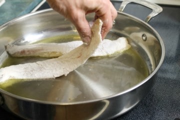 placing flour dusted haddock in a hot frying pan