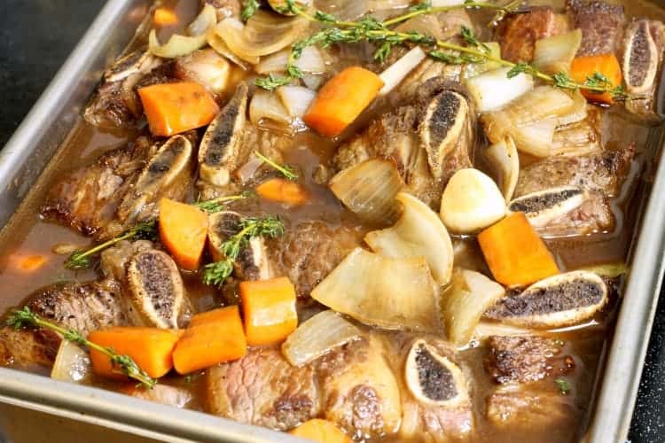 seared short ribs covered in braising liquid ready for the oven