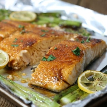 Brown sugar glazed salmon on a tinfoil lined pan surrounded by asparagus