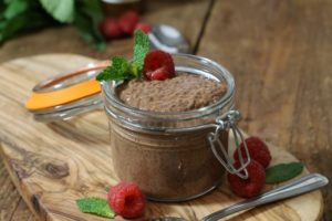 Chocolate chia seed pudding in a small mason jar garnished with raspberries and mint