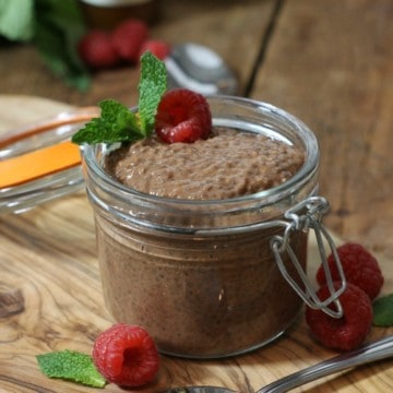 Chocolate chia seed pudding in a small mason jar garnished with raspberries and mint