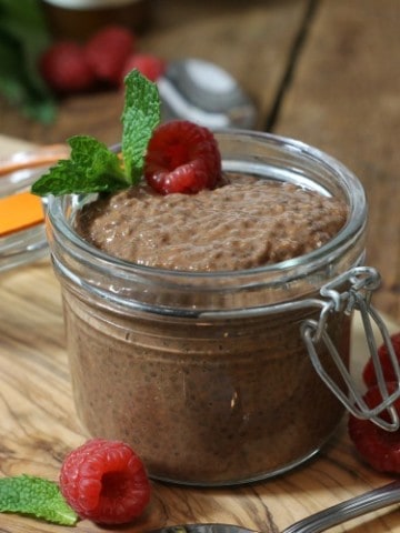 Chocolate chia seed pudding in a small mason jar garnished with raspberries and mint