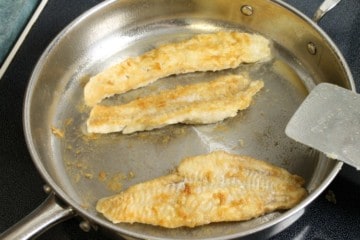 pan fried haddock finishing in a steel frying pan