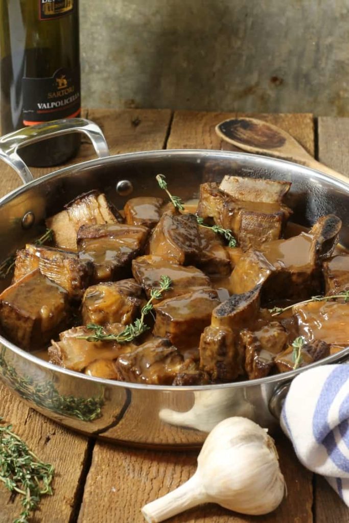 Braised short ribs covered in a rish sauce and served in a large steel pan