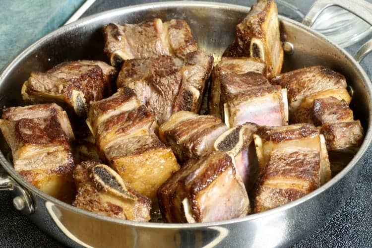 golden brown seared beef short ribs in a frying pan