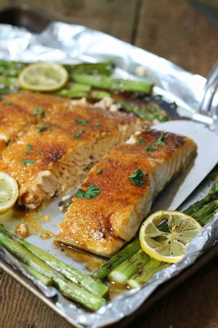 Baked salmon glazed with brown sugar and cut into portions on a tinfoil lined sheetpan