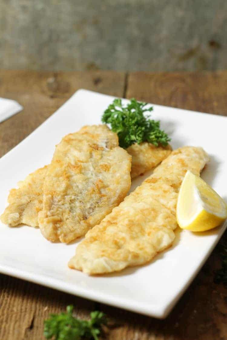 crispy pan fried haddock garnished with parsley and lemon, ready to eat
