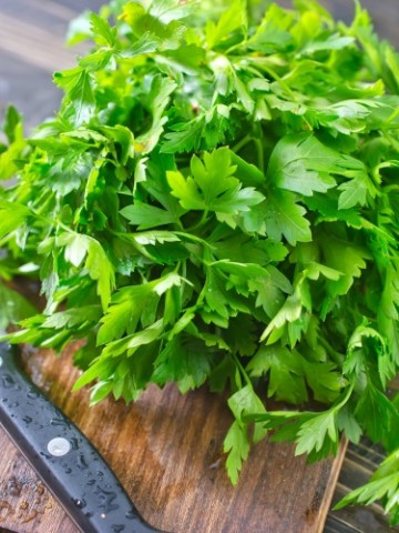 reshly harvested Italian parsley on a wooden cutting board