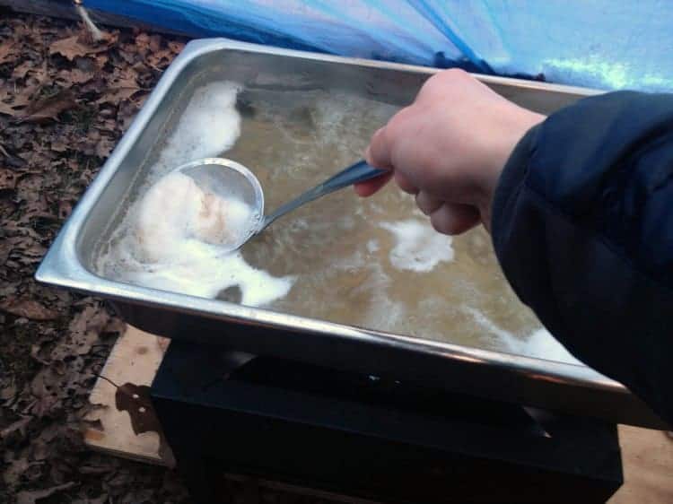 skimming maple sap as it boils down while making maple syrup.