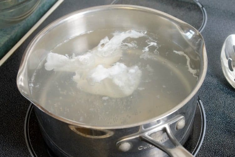 partially poached eggs in  a pot of water.