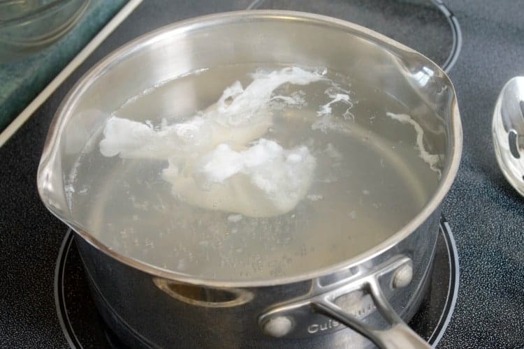 partially poached eggs in a pot of water.