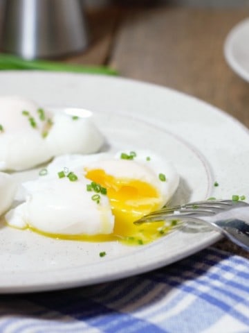 cut open poached eggs on a breakfast plate