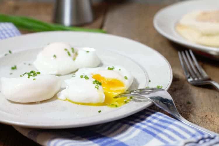 cut open poached eggs on a breakfast plate