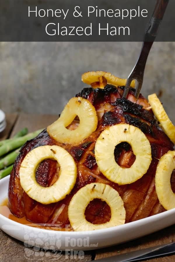 pinterest image of honey and pineapple glazed ham with a carving fork stuck in it