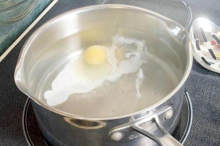 raw egg just dropped into poaching water