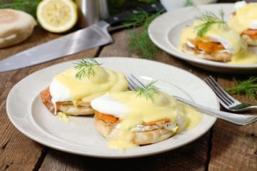 smoked salmon eggs benedict garnished with dill on a white plate