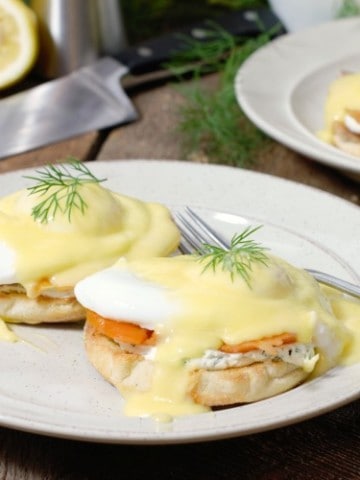 smoked salmon eggs benedict garnished with dill on a white plate