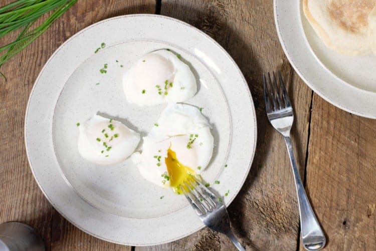 overhead shot of poached eggs served on a plate and garnished with chives