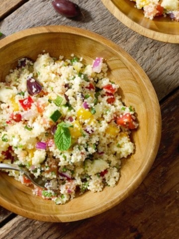 overhead shot of a wooden bowl filled with Mediterranean Couscous Salad